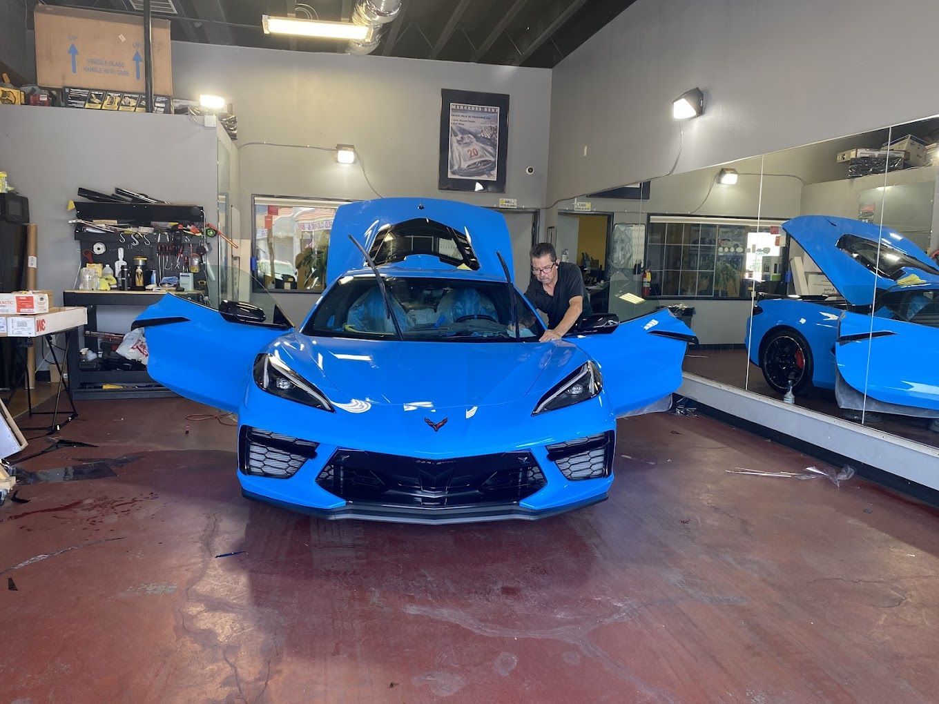 A man is working on a blue sports car in a garage.
