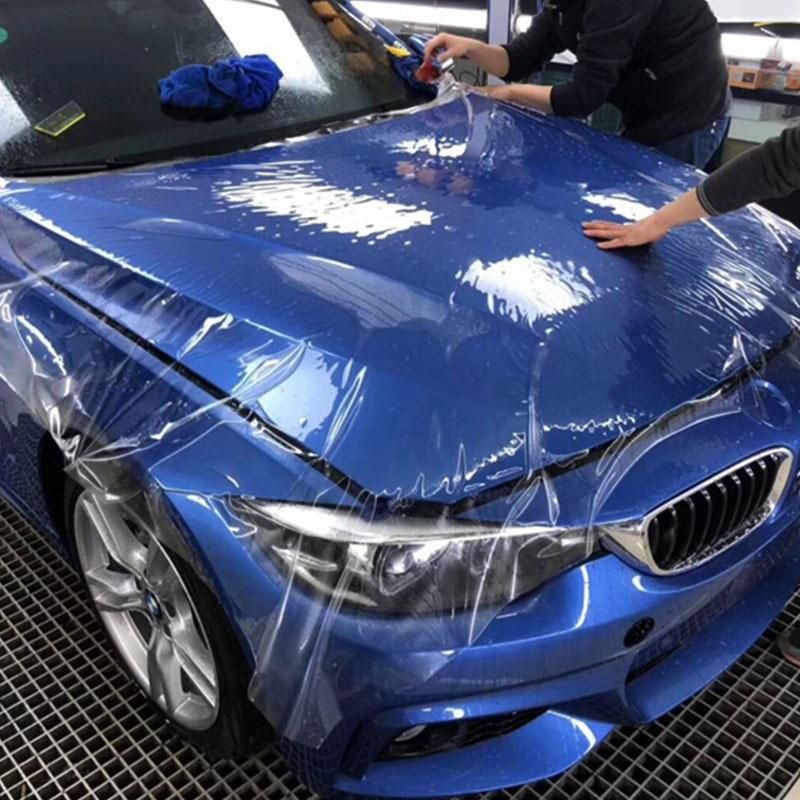 A blue bmw is being wrapped in plastic
