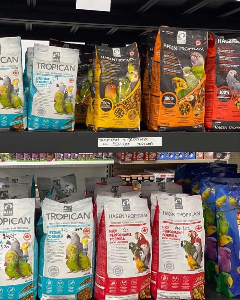 Shelves of Bird Food Bags, Various Colours, With Parrot Illustrations — Jonath’s Animal Kingdom in Forster, NSW