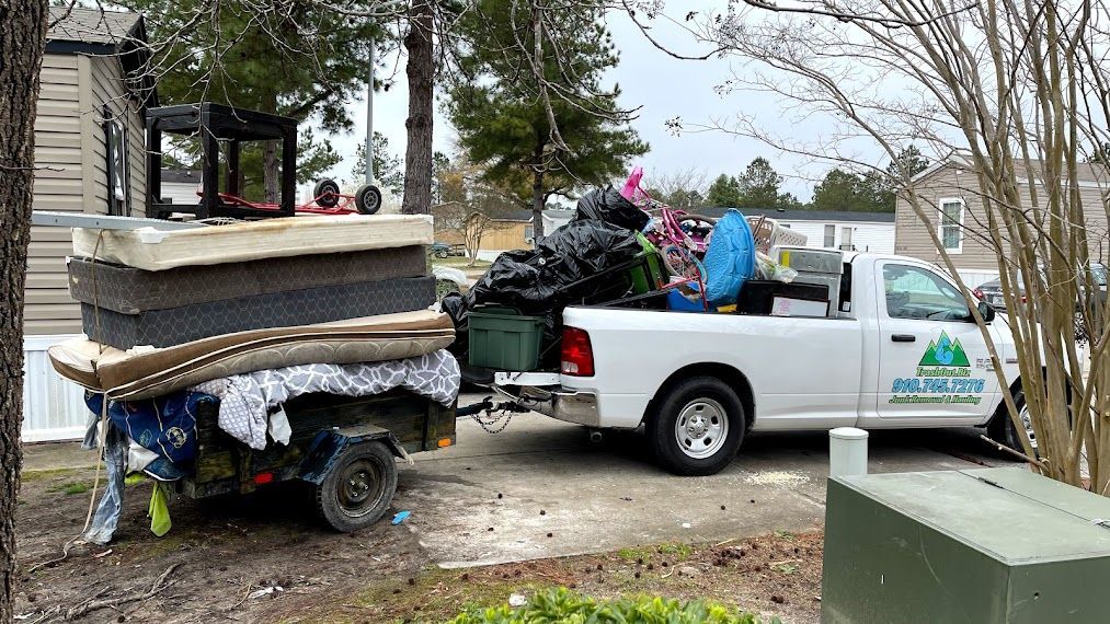White truck with trailer overloaded with household items in a residential area.