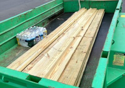 Green truck bed loaded with lumber and a pack of bottled water.