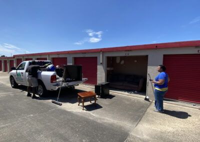 People unloading furniture from a truck at a storage unit on a sunny day.