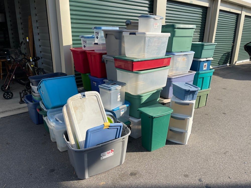 Storage unit entrance with a large pile of plastic bins in various colors.