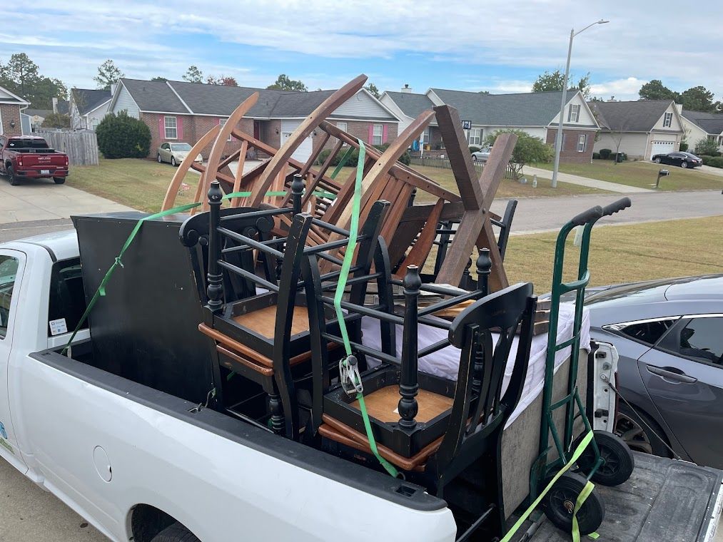 Pickup truck loaded with furniture, secured with straps, in a suburban setting.