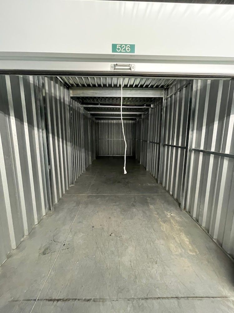 An empty storage unit, showing a long, narrow space with a door open. Unit number is 526.