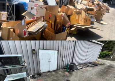Cardboard boxes piled outside a white building, contrasted by a clear space around a doorway.