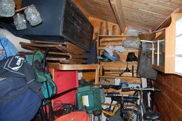 Cluttered shed interior with bike, shelves, and various items.