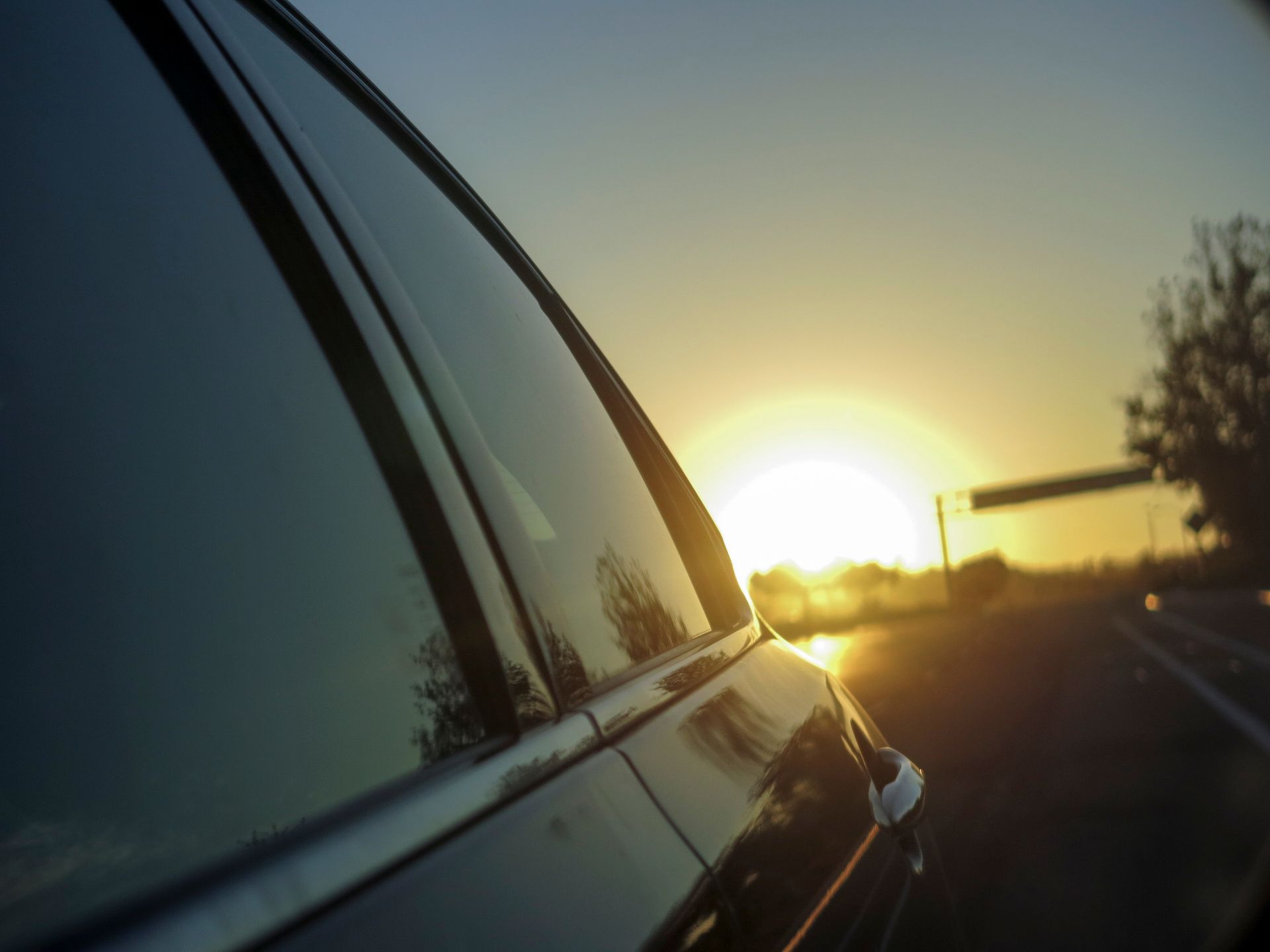 A car is driving down a highway at sunset.