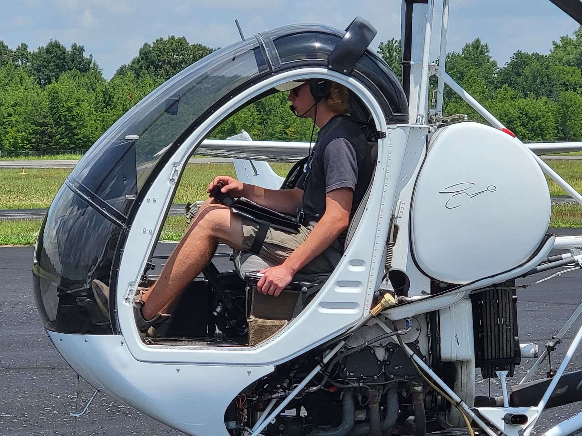 A man is sitting in the cockpit of a small helicopter