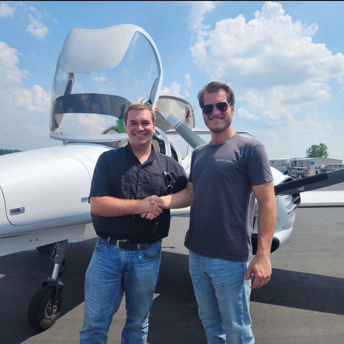 Two men are standing in front of a small plane.