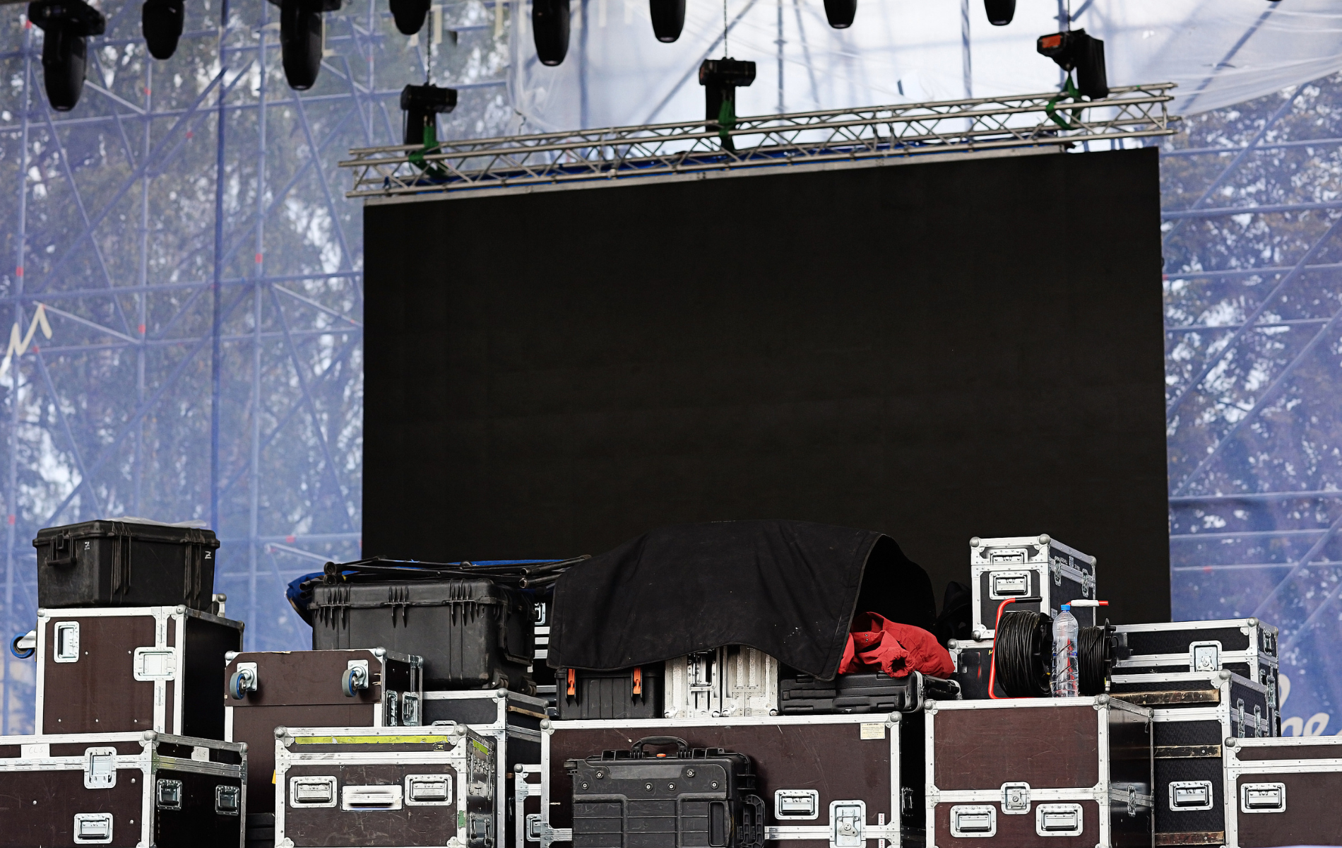 Stage setup with a large black screen and equipment cases.