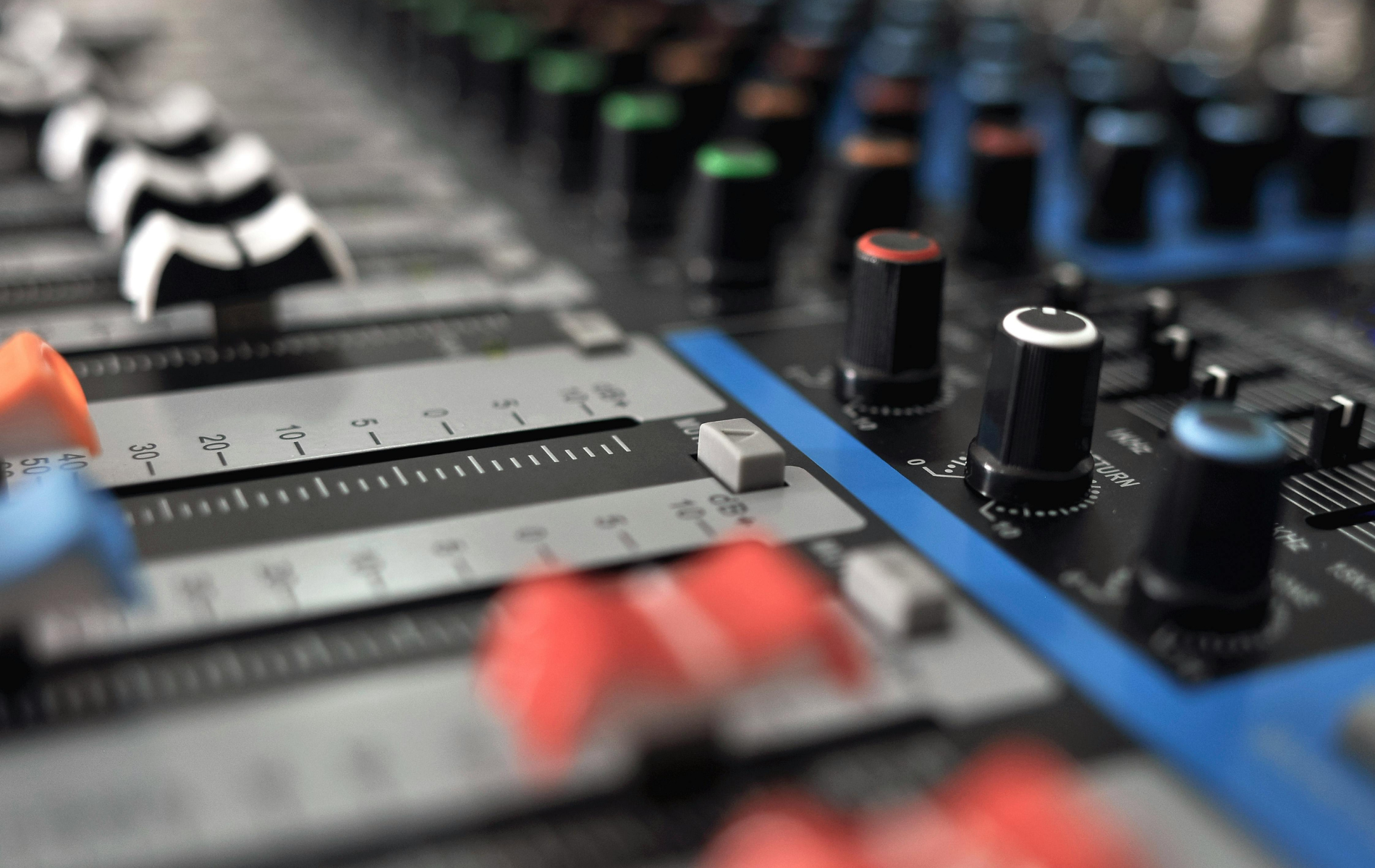 Close-up of a blue and gray sound mixing console with various knobs and faders.