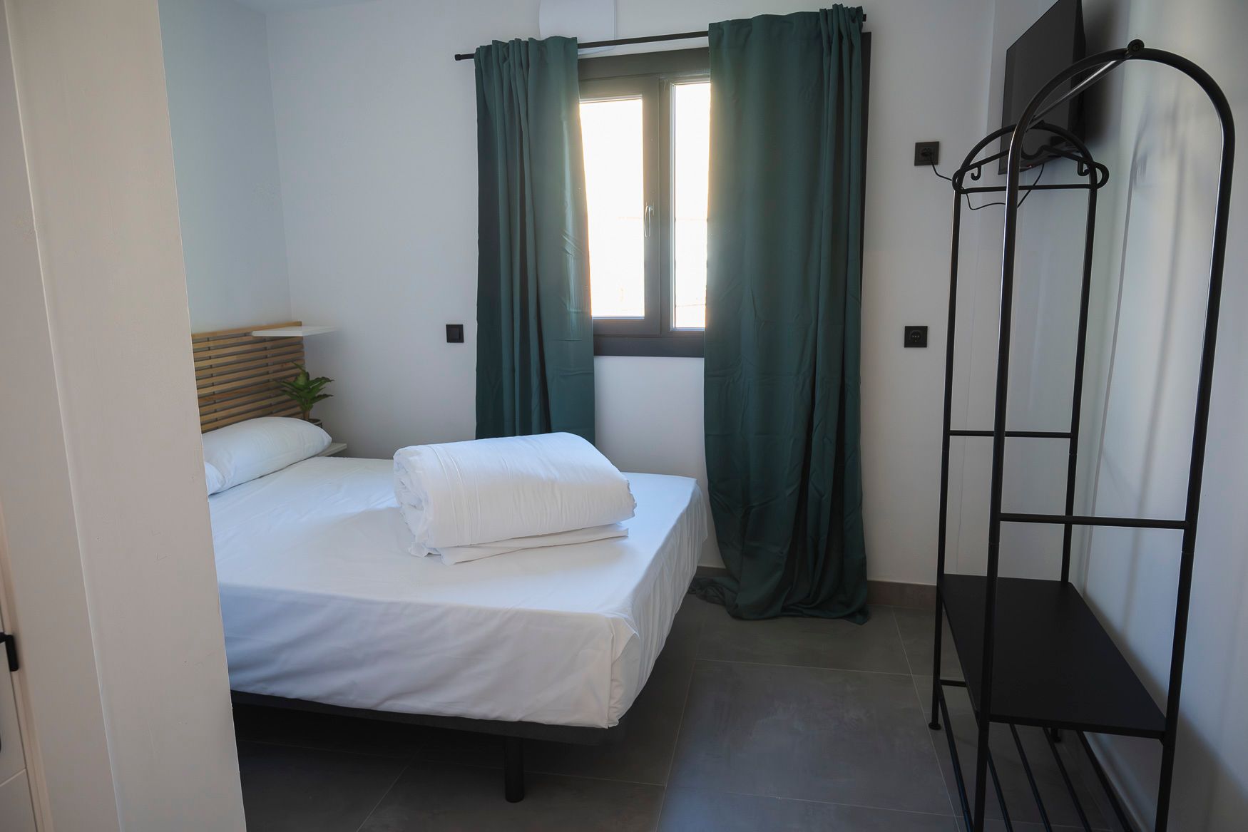 Literas en una habitación de albergue con paredes amarillas, marcos negros y pasillo estrecho.