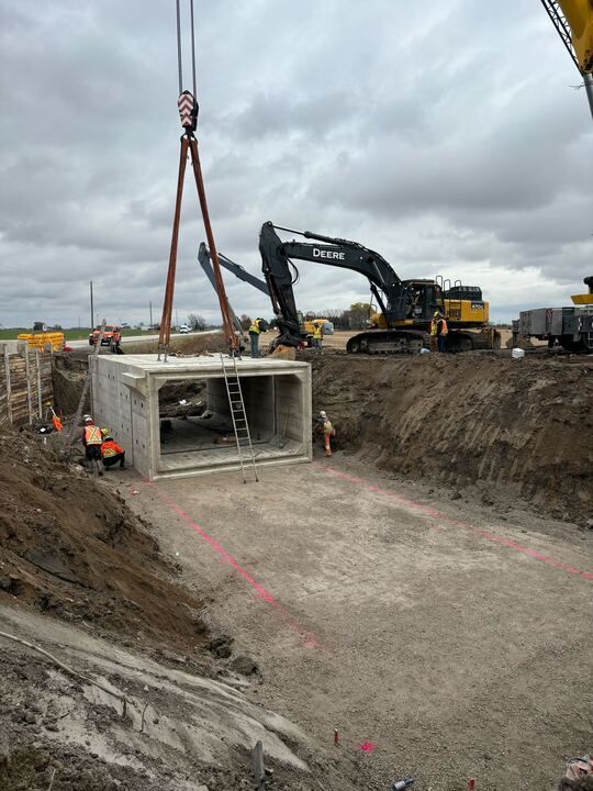 A construction site with a crane lifting a concrete box.