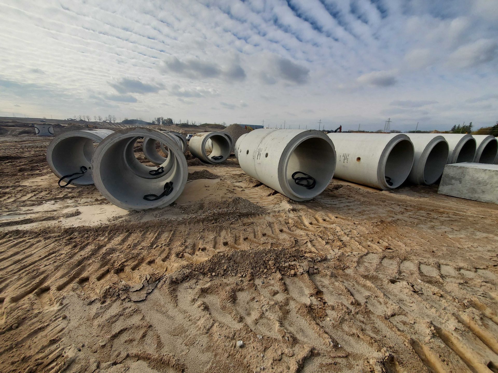 Concrete pipes are stacked on top of each other in a dirt field
