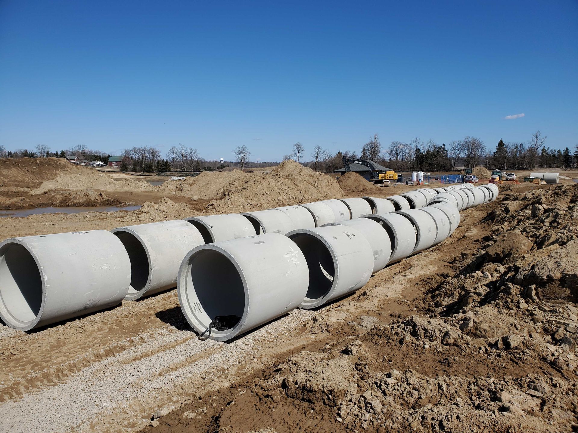 A row of concrete pipes are sitting in the dirt on a construction site.