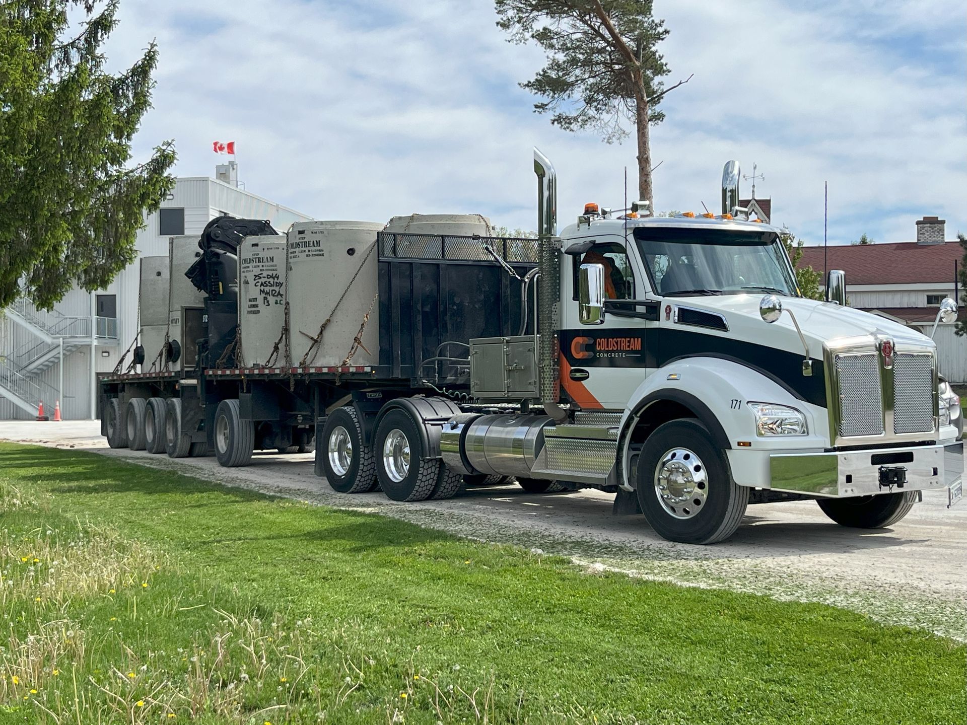 A semi truck is parked on a dirt road next to a grassy field.