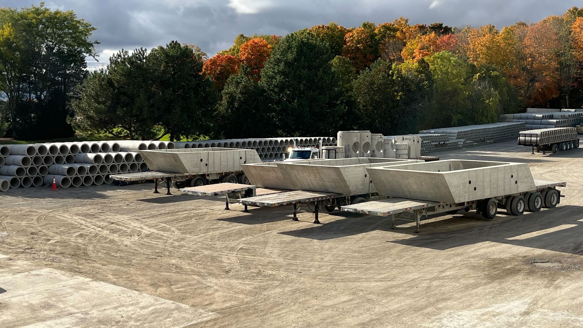 A row of trailers are parked in a dirt lot with trees in the background.