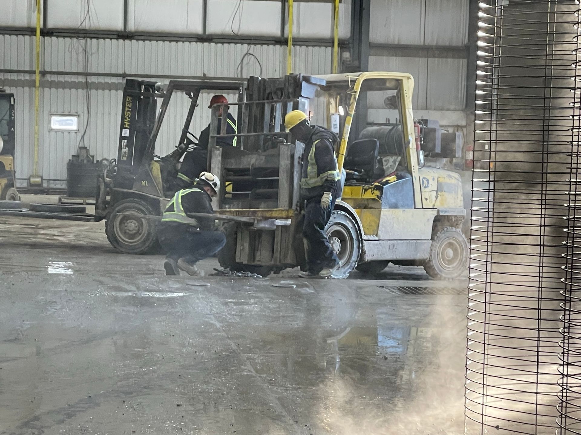 A man is working on a forklift in a warehouse.