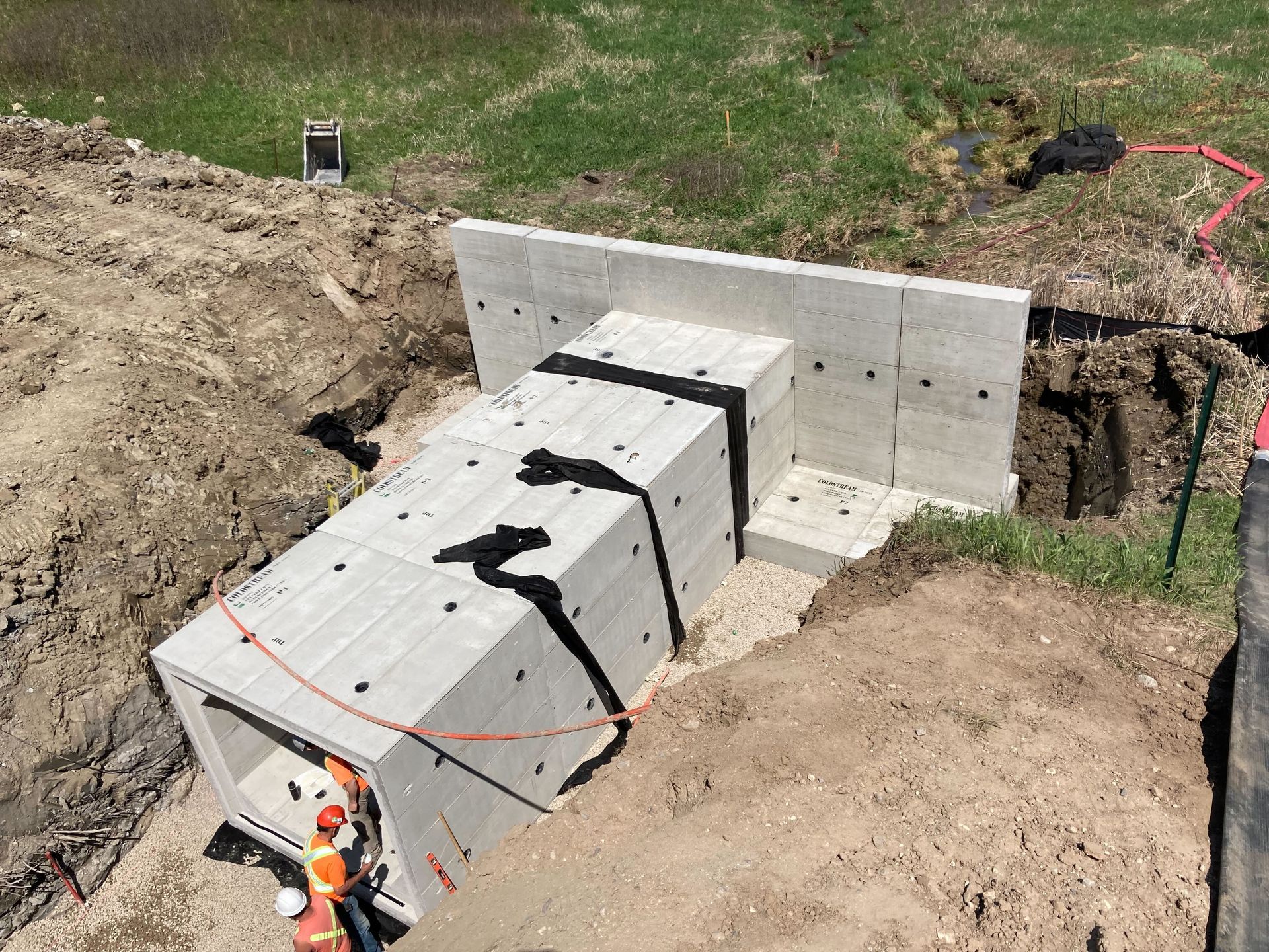 A group of construction workers are working on a large concrete structure in the dirt.