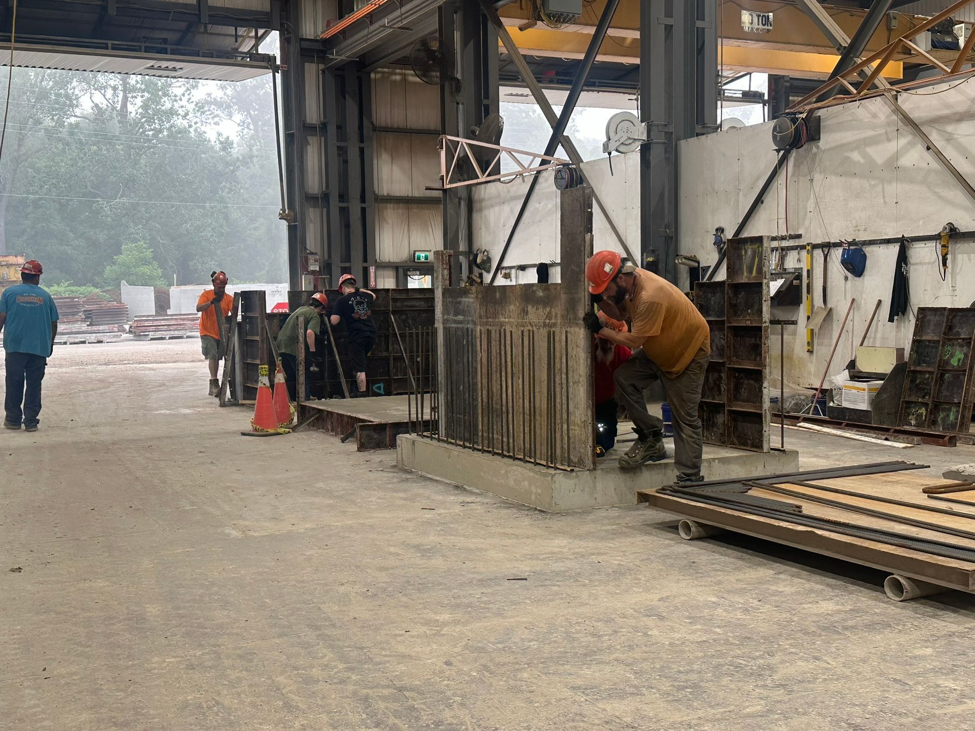 A man in a hard hat is working on a piece of metal in a factory.
