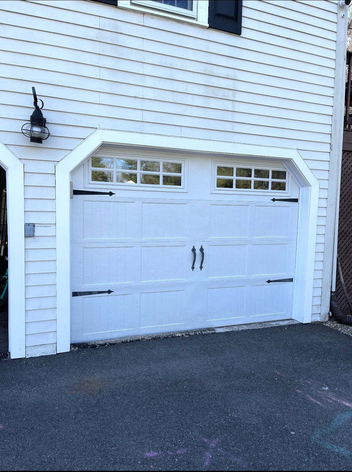 A white garage door on a white house