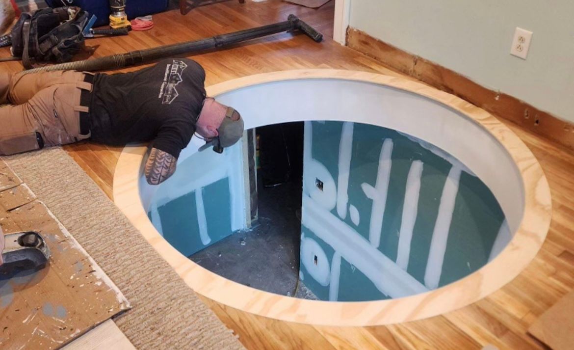 A man is laying on the floor in a hole in the floor.