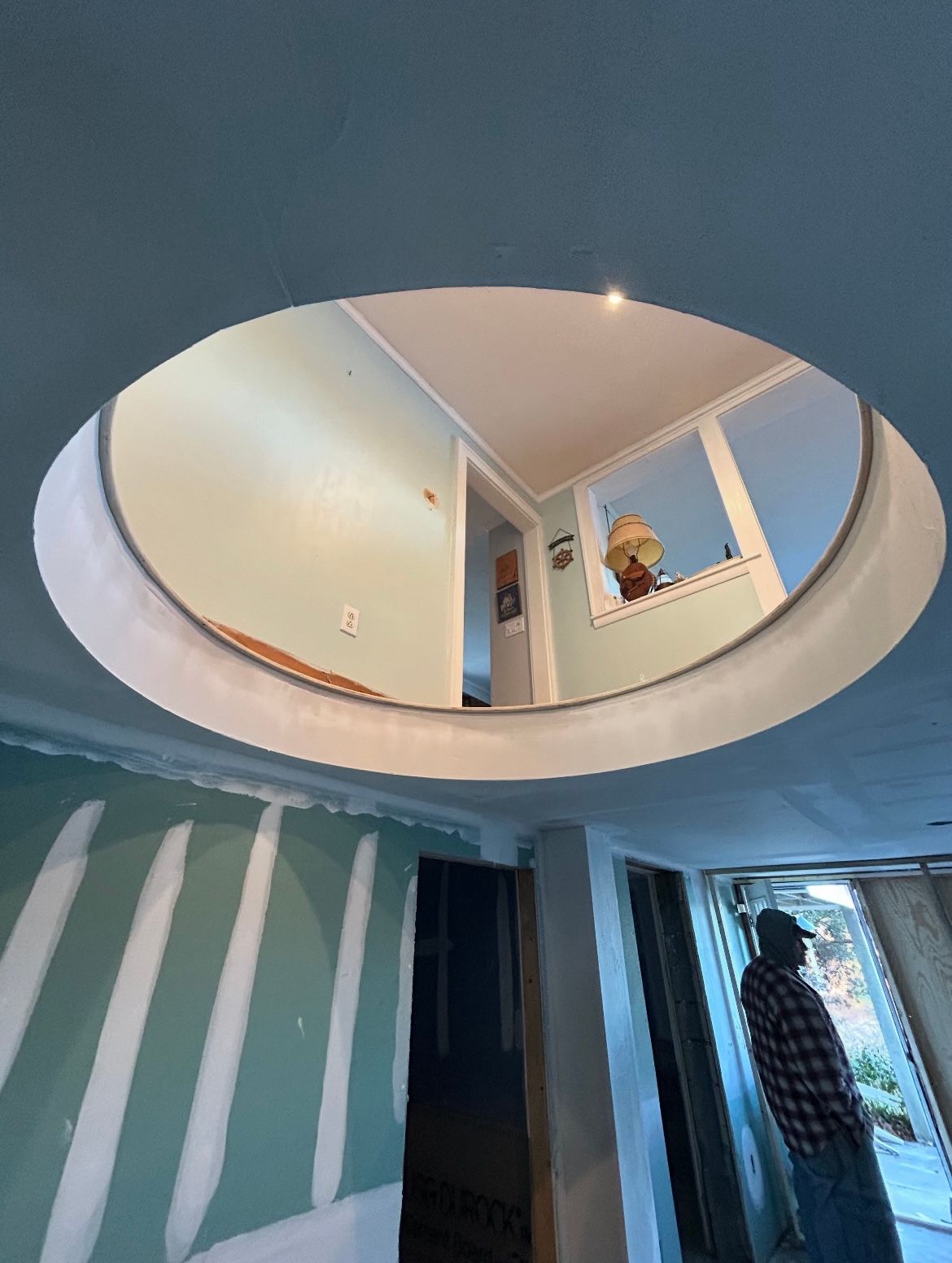 A man is standing in a room with a round window in the ceiling.