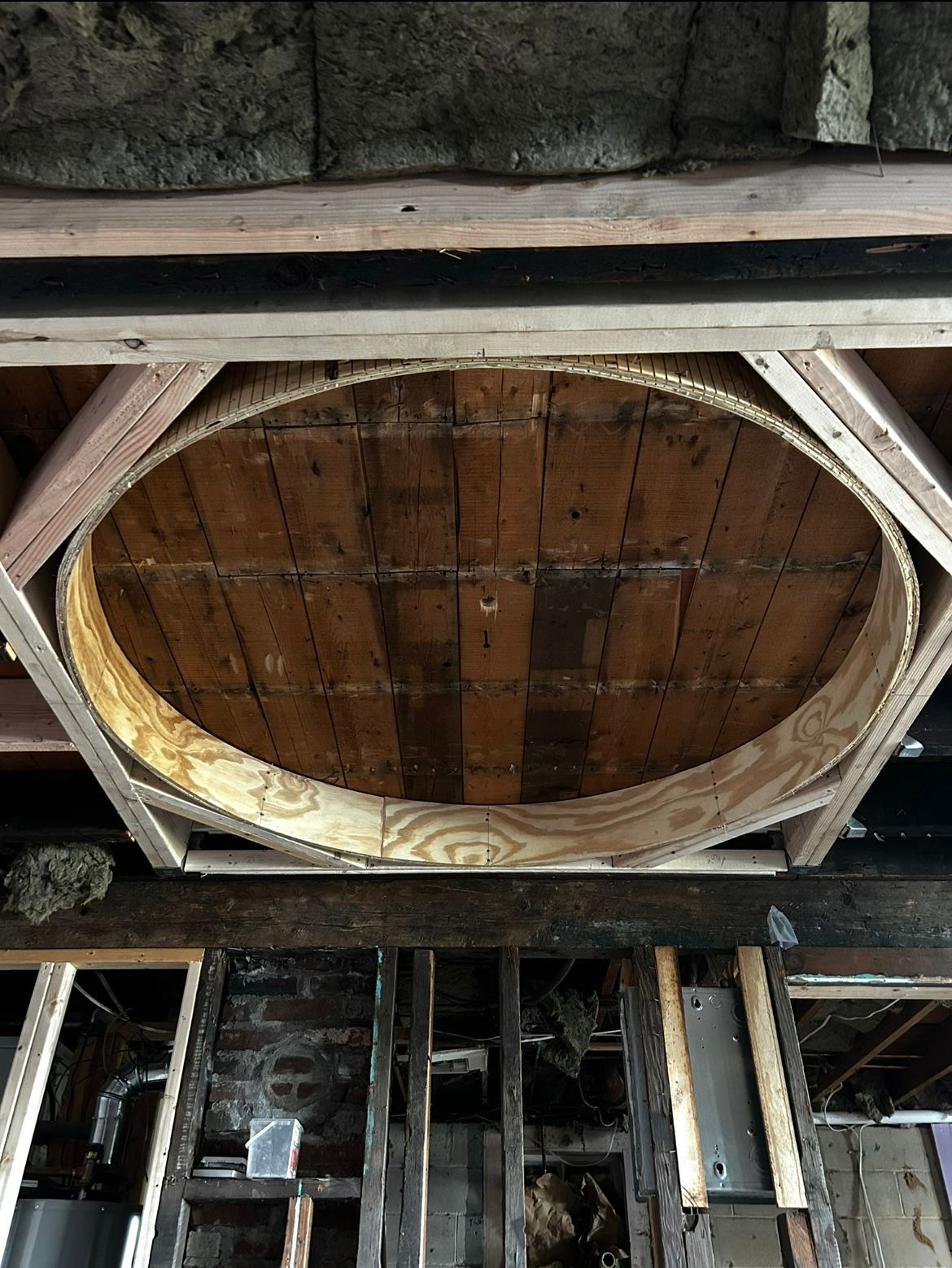 A wooden circle is being built into the ceiling of a building.