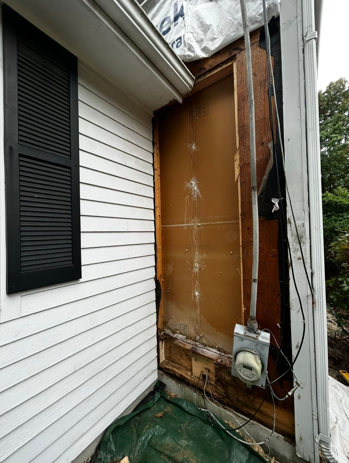 A white house with a brown wall and a black window.