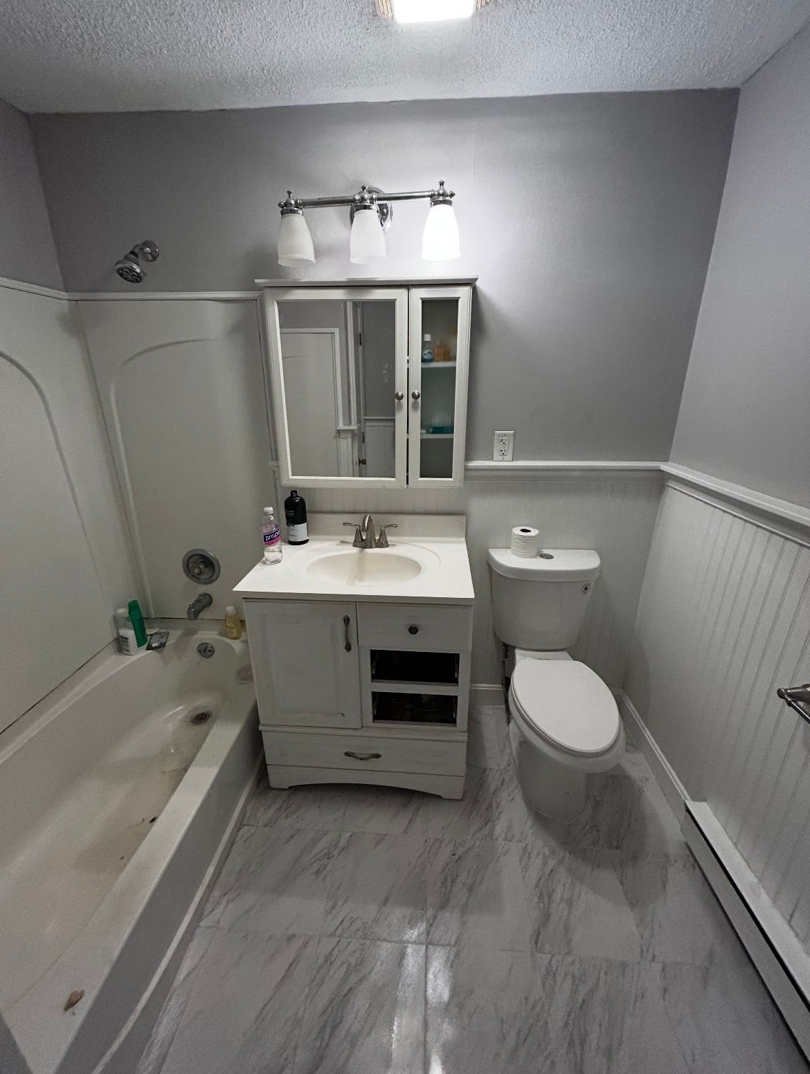 A bathroom with a sink , toilet , bathtub and mirror.