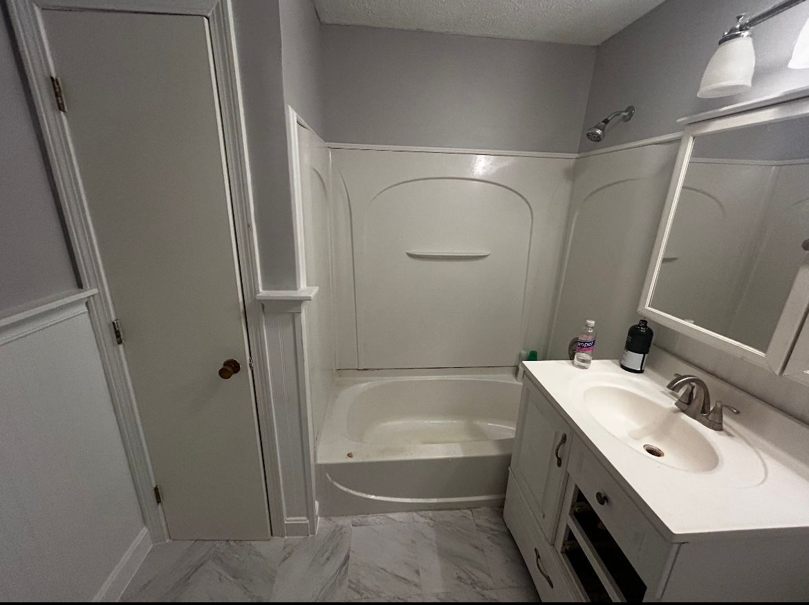 A bathroom with a sink , tub and mirror