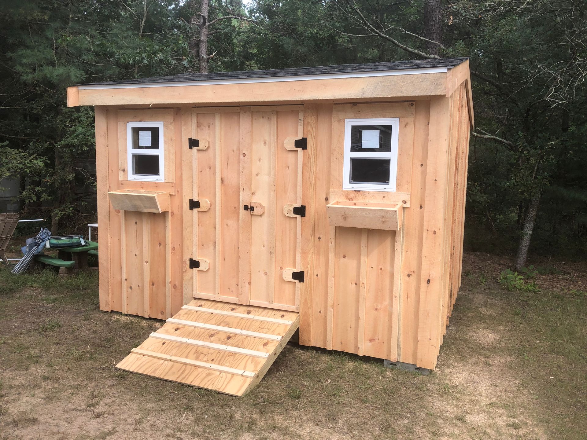 A wooden shed with a ramp and two windows.
