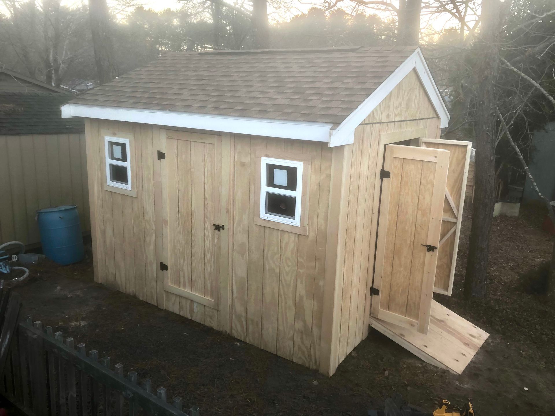 A wooden shed with two windows and a ramp.