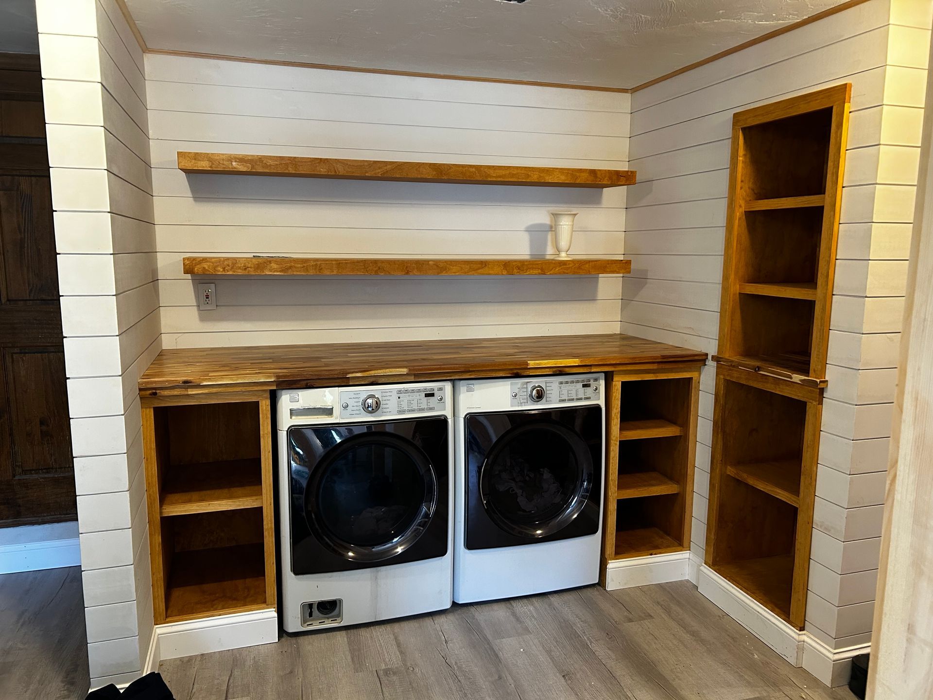 A laundry room with a washer and dryer and shelves