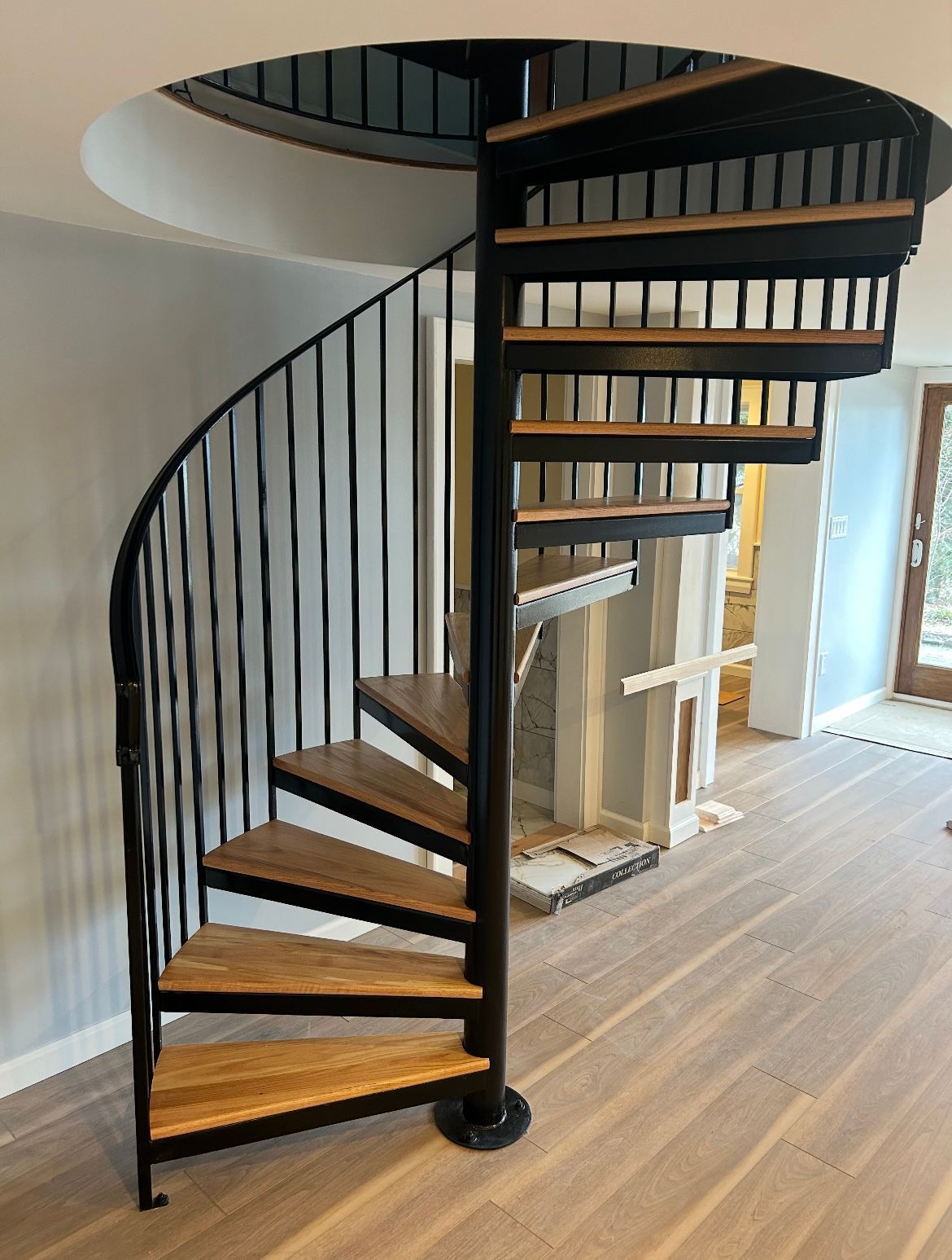 A spiral staircase with wooden steps and a black railing in a room.