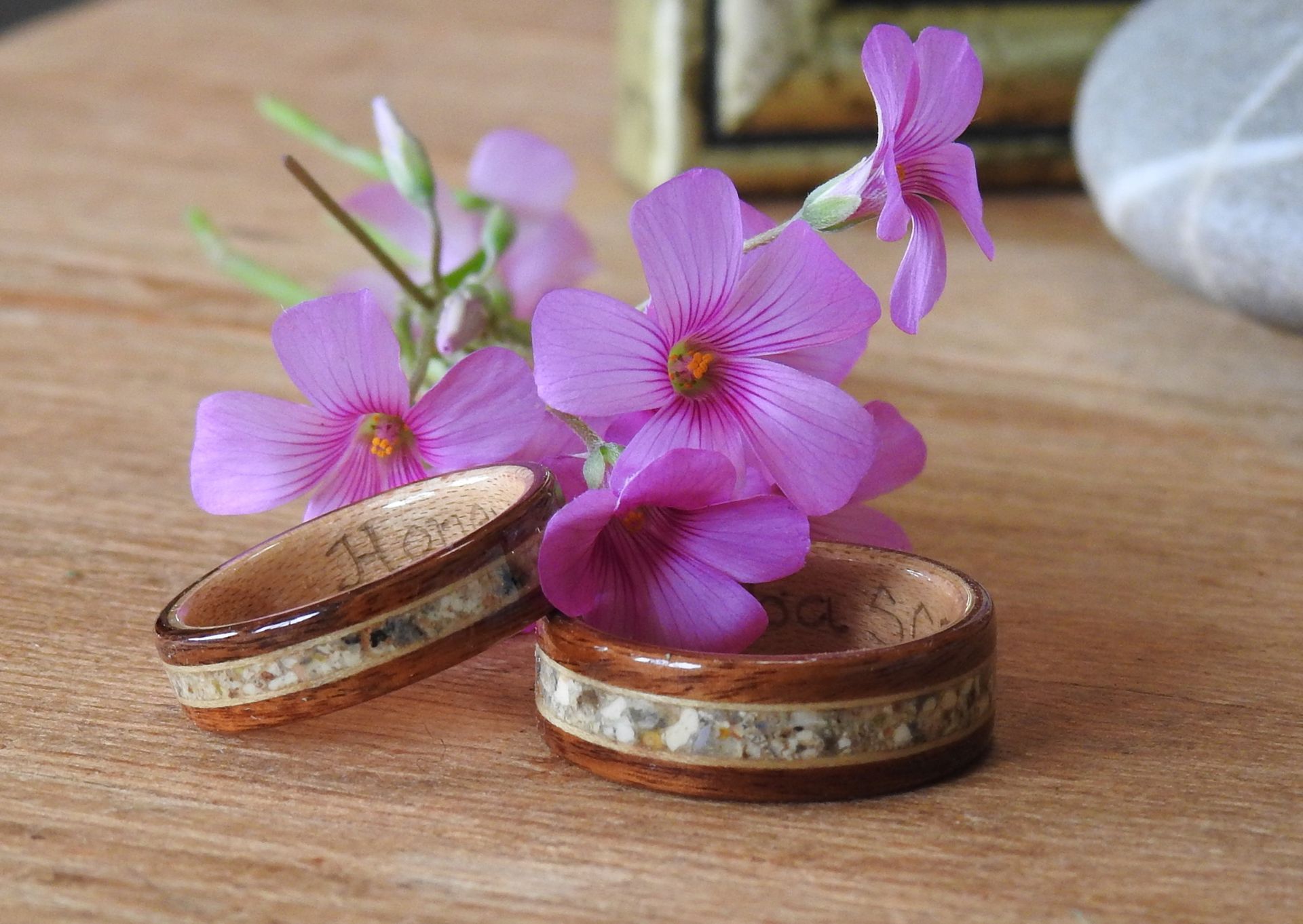 Cocobolo wood rings with Maple inlaid with a beloved pups ashes. The rings sit with tiny pink flowers on wood