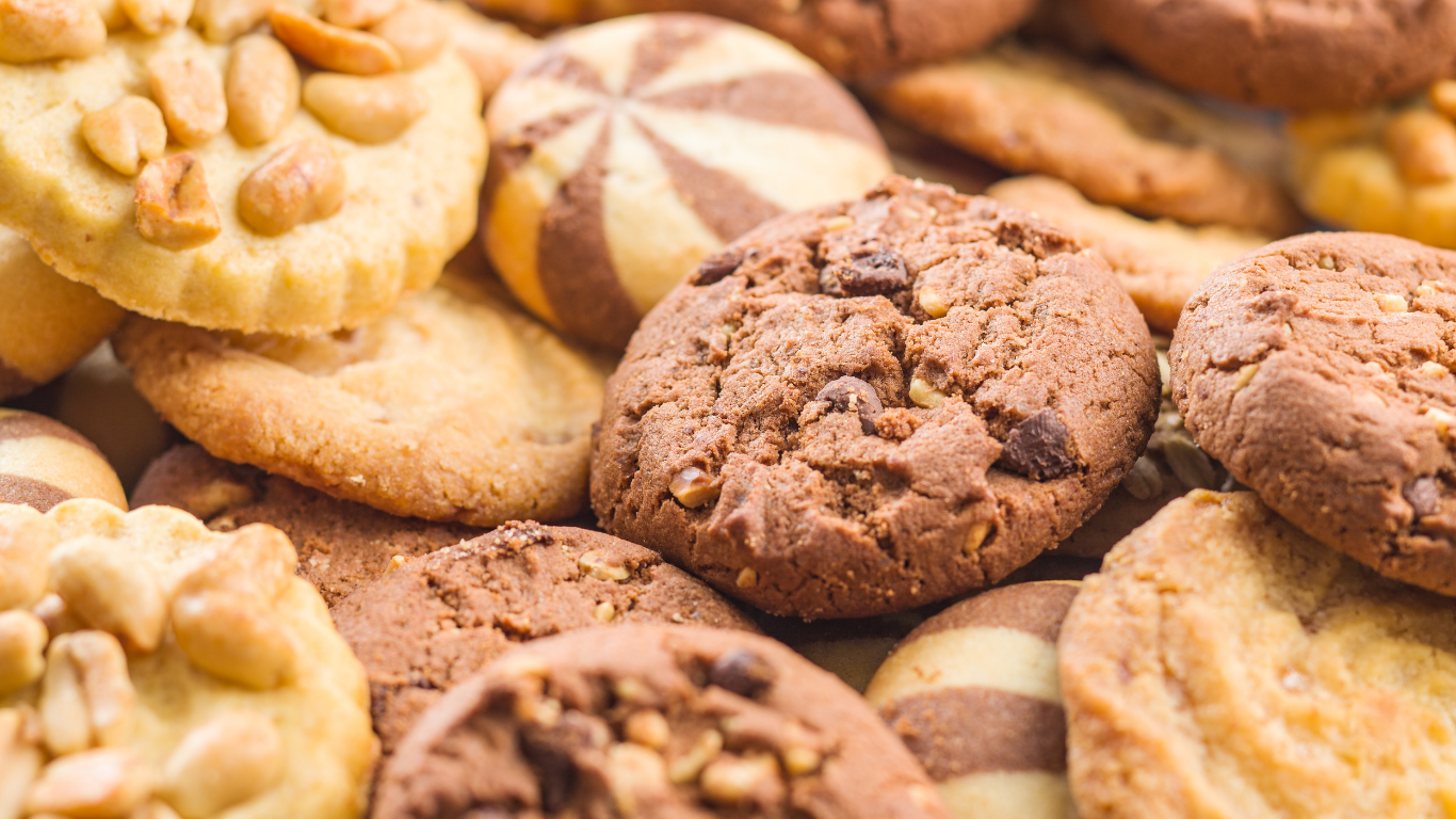 A close-up pile of various types of cookies, including peanut, chocolate chip, and striped shortbread varieties.