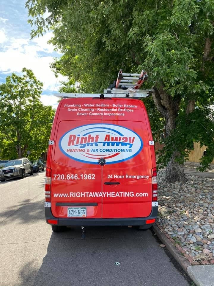 Four red service vans parked in front of a stone-faced building with the