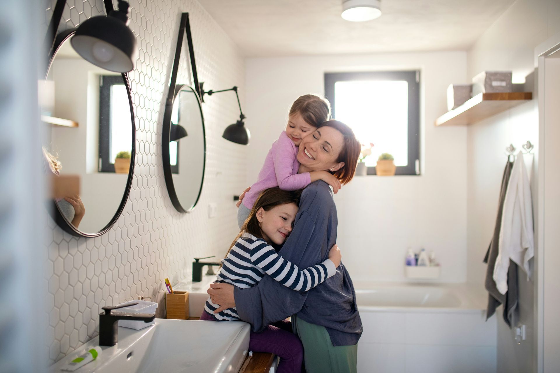 Couple sitting in doorway, drinking from mugs, smiling. Indoor, plants, radiator, wood floor.