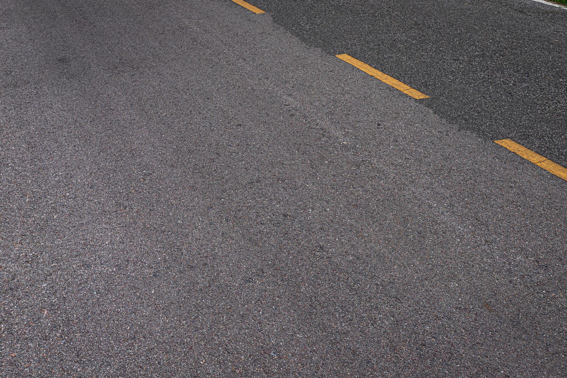 A close up of a road with a yellow line on it.