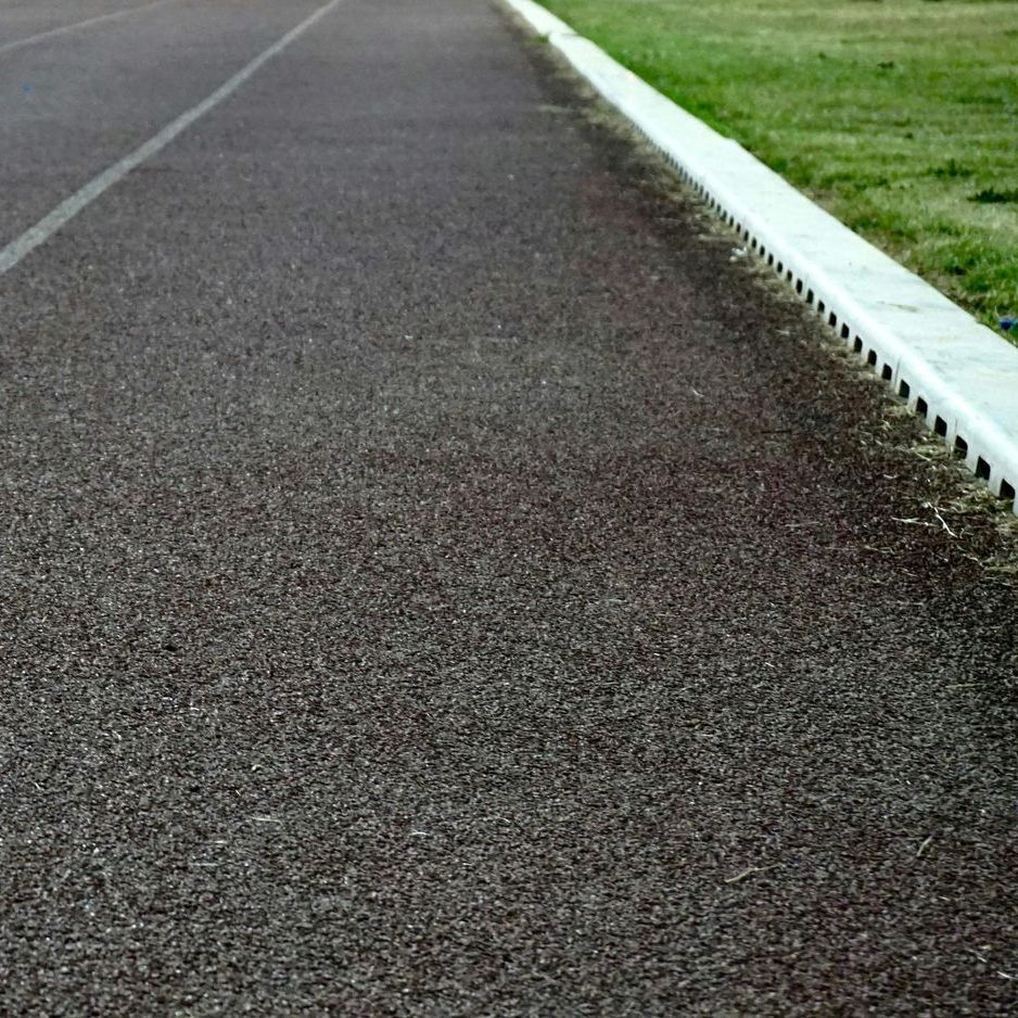 A running track with a white curb and grass on the side