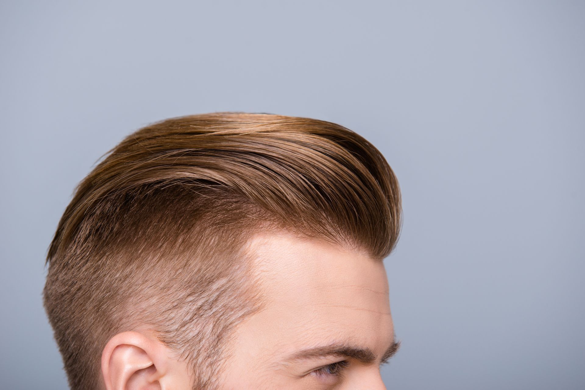 A close up of a man 's hair on a gray background.