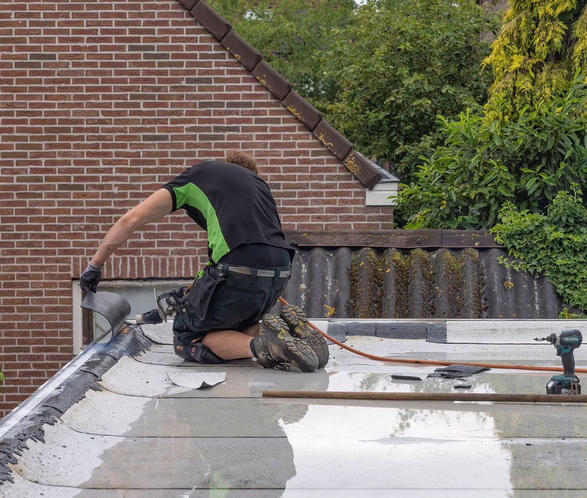 a man is kneeling on the roof of a house .