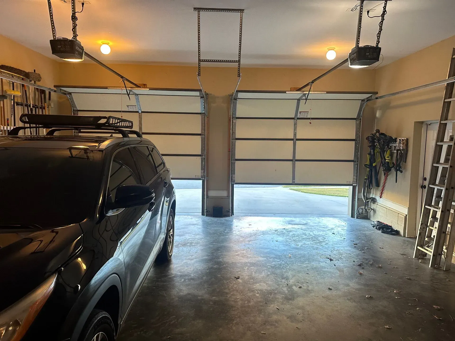 A truck is parked in a garage with two garage doors open.
