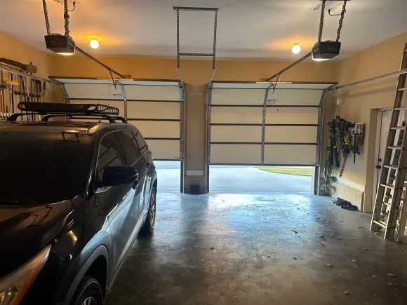 A truck is parked in a garage with two garage doors open.