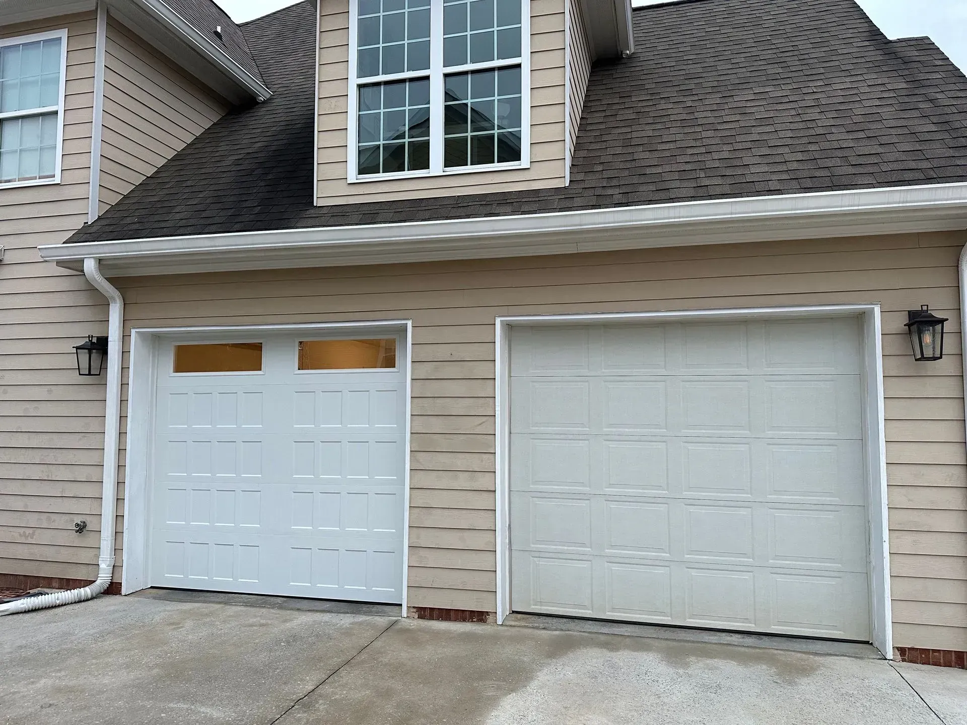 A house with two white garage doors and a brown roof