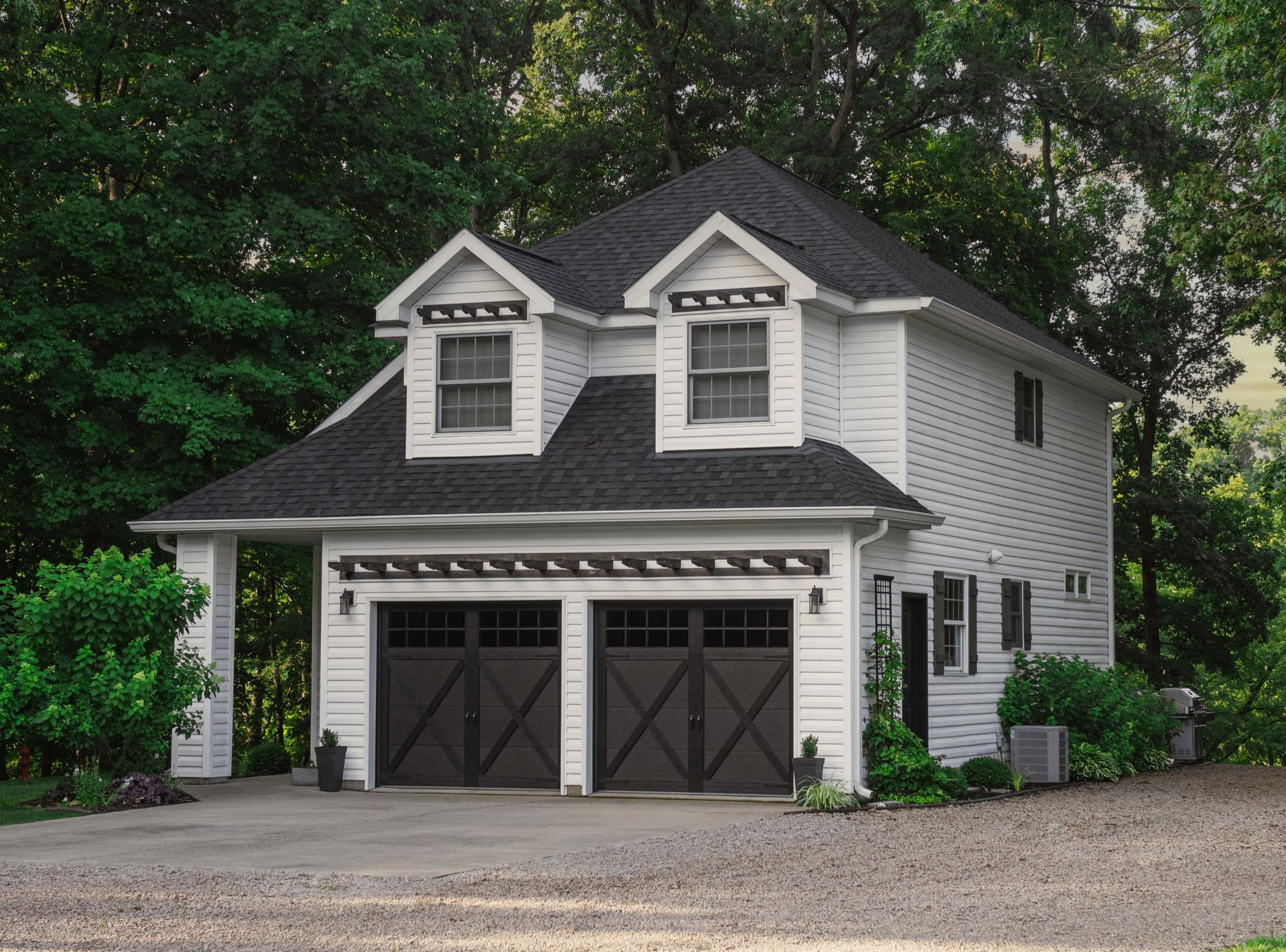 A house with two white garage doors and a brown roof