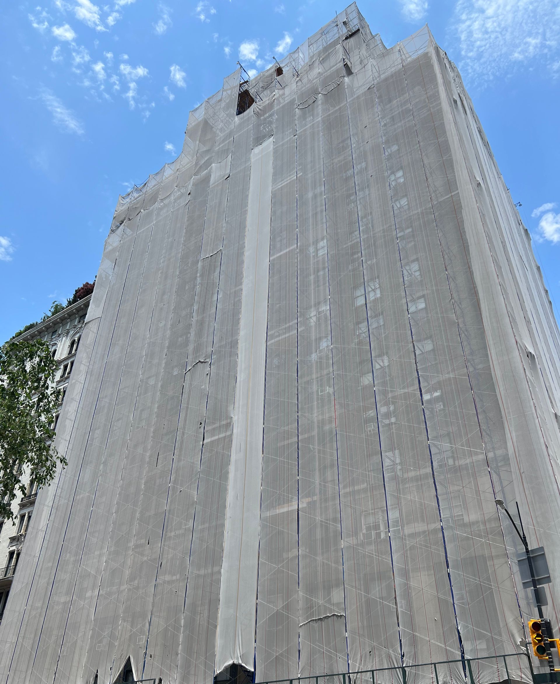 A very tall building is covered in scaffolding on a sunny day