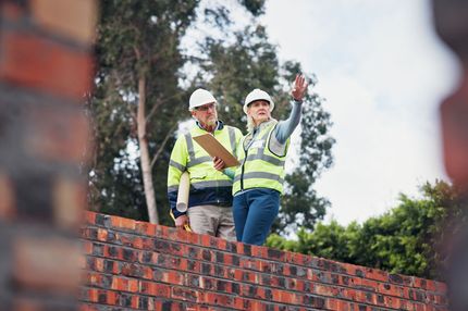 A man and a woman are standing on top of a brick wall.